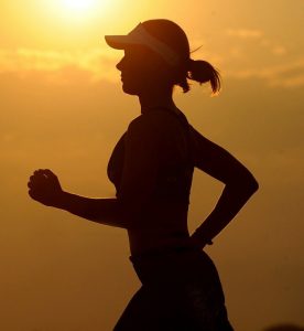 Woman running against a sunset.